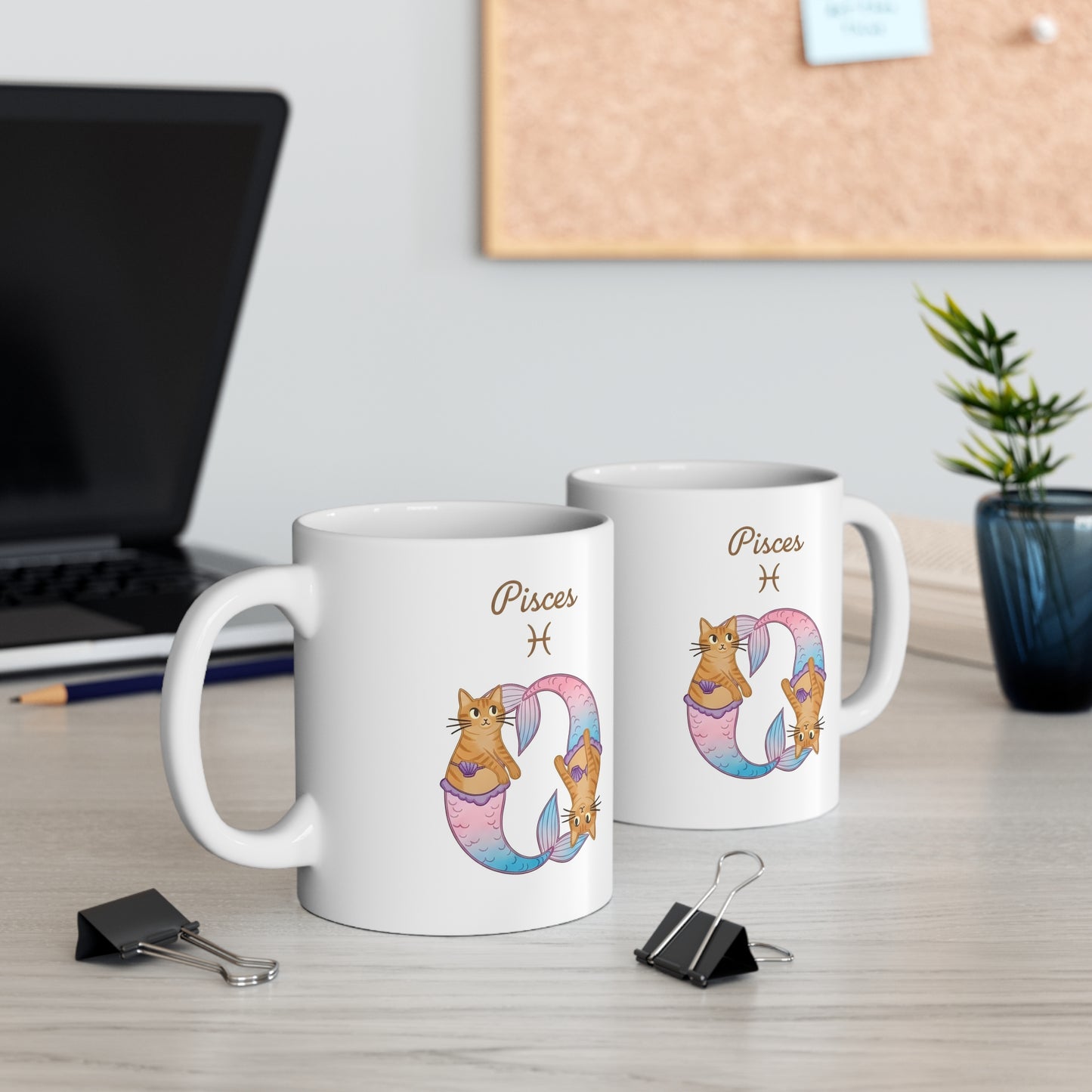 Two mugs with Pisces zodiac design on a desk with office items.