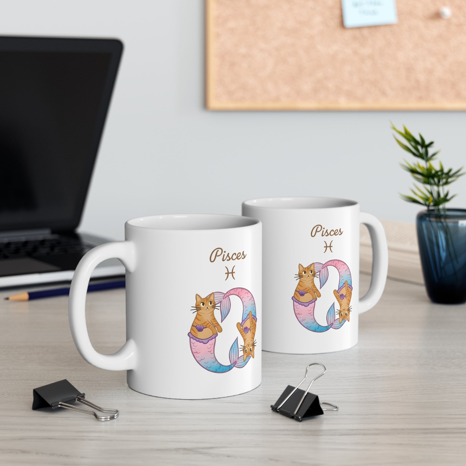Two mugs with Pisces zodiac design on a desk with office items.